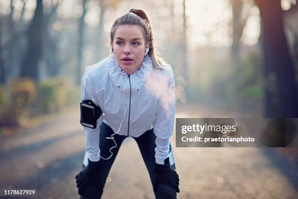 jong meisje rust uitgeput na run in mistige ochtend - zichtbare adem stockfoto's en -beelden