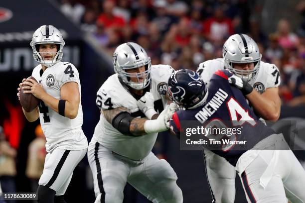 Derek Carr of the Oakland Raiders looks to pass under pressure by Charles Omenihu of the Houston Texans in the fourth quarter at NRG Stadium on...