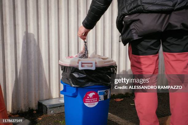 Marianne Mayer, dog trainer, throws some trash in a bin with a sticker reading "Do you want to give poo a new life?" in Vantaa, Finland on October 7,...