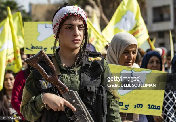 Member of the Kurdish internal security services known as Asayish stands guard during a demonstration by Syrian Kurds against the Turkish assault on...