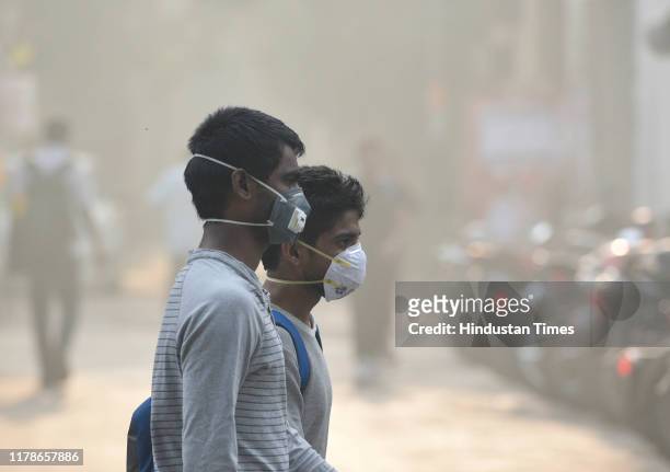 People wearing pollution masks to protect against air pollution as heavy smog descends on the national capital, a day after Diwali, near Ashram, on...