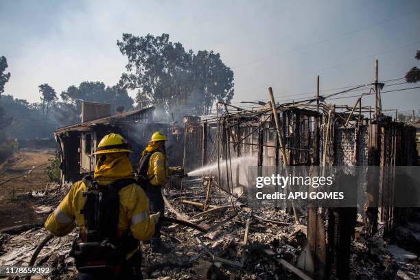 Firefighters battle the Getty Fire in houses on fire in Brentwood, California on October 28, 2019. - A wildfire broke out early Monday near the...