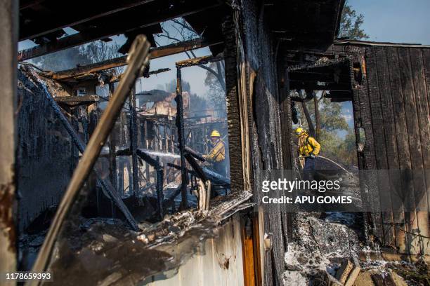 Firefighters battle the Getty Fire in houses on fire in Brentwood, California on October 28, 2019. - A wildfire broke out early Monday near the...