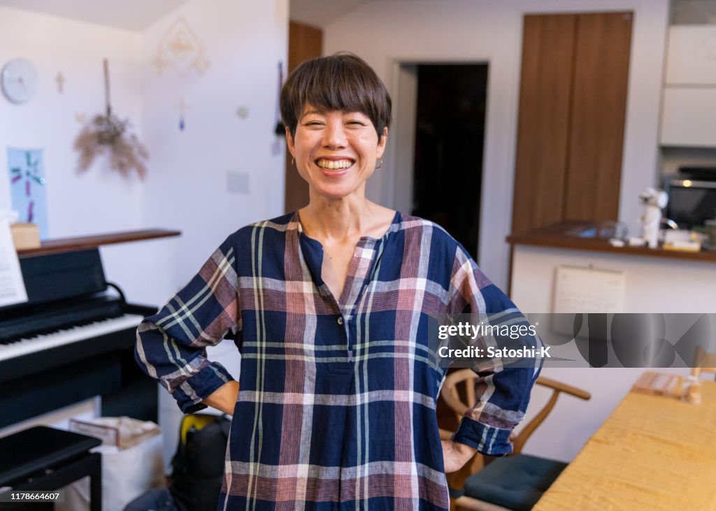 Portrait of Japanese mother standing in dining room with toothy smile