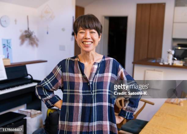 portrait of japanese mother standing in dining room with toothy smile - the japanese wife stock pictures, royalty-free photos & images