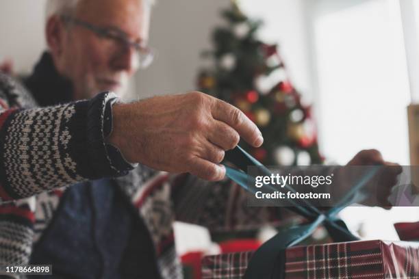 aus einem mann herausschneiden, der einen bogen auf ein weihnachtsgeschenk bindet - gift wrap stock-fotos und bilder