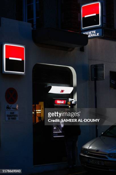 Man uses the cash machine of the Societe Generale bank, in Ouistreham, Normandy, northwestern France, on October 28, 2019.