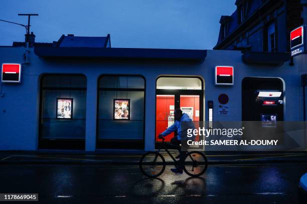 Man rides a bike in front of a Societe Generale bank in Ouistreham, Normandy, northwestern France, on October 28, 2019.