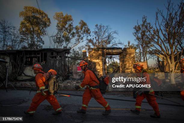 Inmate firefighters walk past a burnt home on Tigertail road during the Getty Fire in Brentwood, California, on October 28, 2019. More than 1,000...