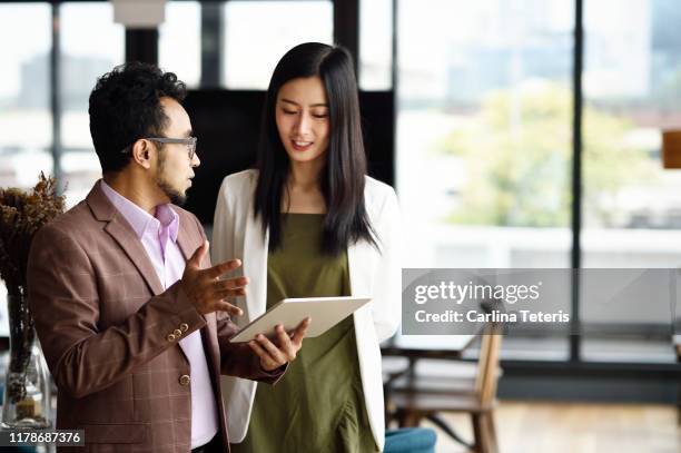 colleagues working from a tablet in an office together - advanced singapore fotografías e imágenes de stock