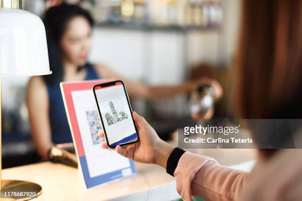 woman making a qr code payment in a bar - bar code ストックフォトと画像