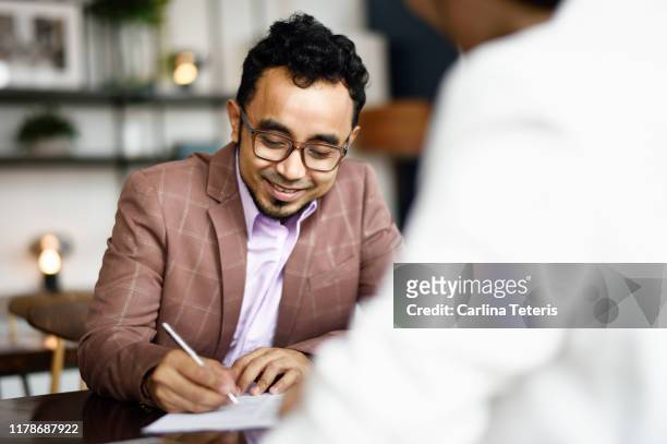 Malay man signing papers at a business meeting
