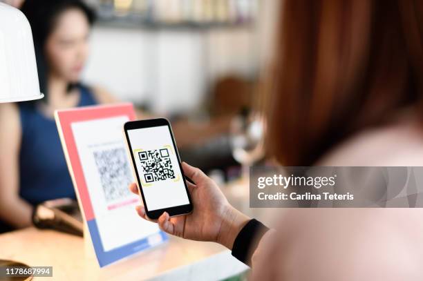 woman making a qr code payment in a bar - strichkodeleser stock-fotos und bilder