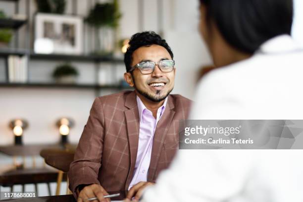 malay man signing papers at a business meeting - zuidoost aziatische etniciteit stockfoto's en -beelden
