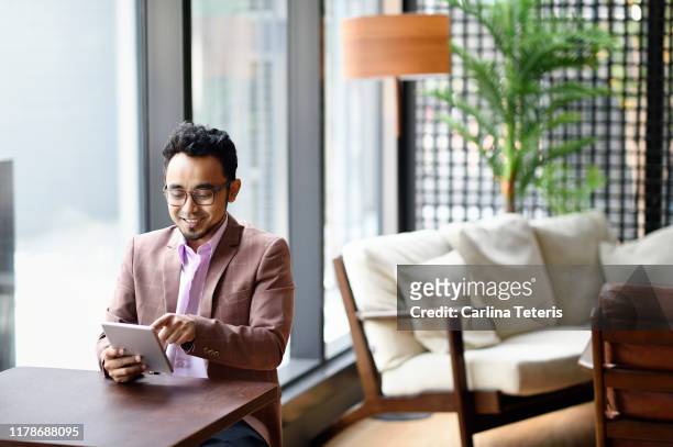 malay man working on a tablet in a co-working office - malay archipelago stock pictures, royalty-free photos & images