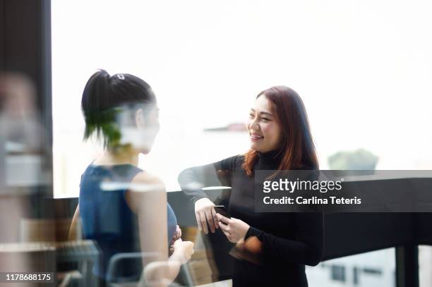 Two business women chatting outside through glass