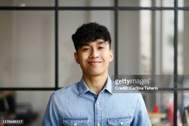 portrait of a young malay man in a modern office - junger erwachsener stock-fotos und bilder