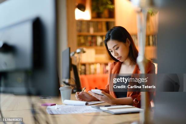 chinese woman working late at night on business plans - asian finance stockfoto's en -beelden