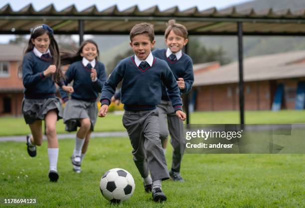 happy kids playing soccer at the school - uniform imagens e fotografias de stock