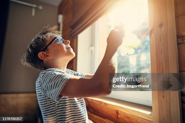 little boy opening the roller blinds in the morning - window with blinds inside stock pictures, royalty-free photos & images