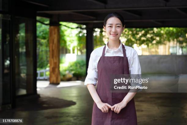 portrait of waitress standing outdoors - apron stockfoto's en -beelden