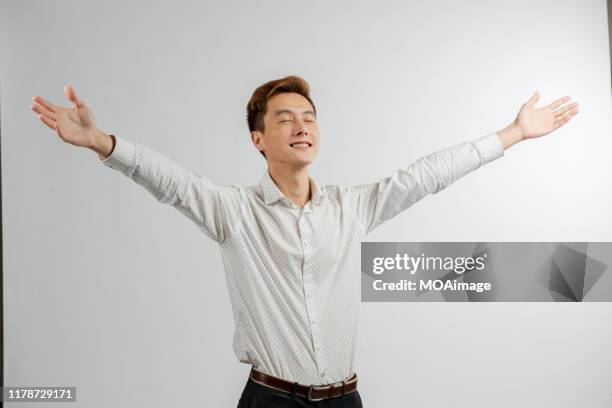 a portrait of an asian businessman in a white shirt in a studio - man outstretched arms ストックフォトと画像