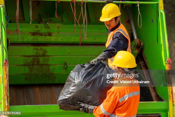 garbage removal men working for a public utility emptying trash container - garbage truck driving stock pictures, royalty-free photos & images