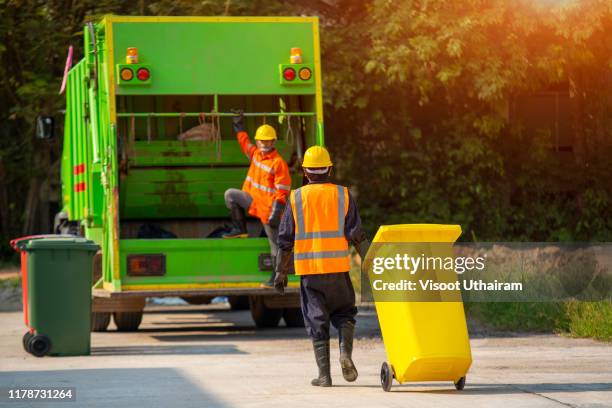 two garbage men working together on emptying dustbins for trash removal - territoriality stock-fotos und bilder