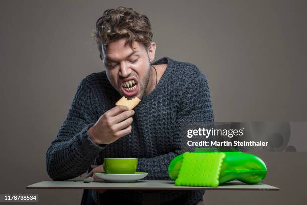 mann mit spitzen zähnen isst keks - vampir - cookie monster stockfoto's en -beelden