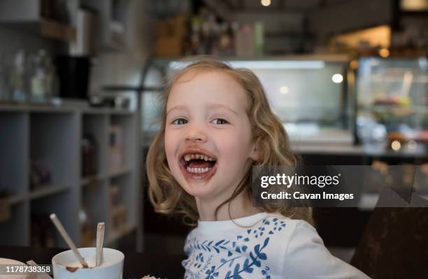 young girl sat in a cafe with chocolate around her mouth - chocolate face stock pictures, royalty-free photos & images