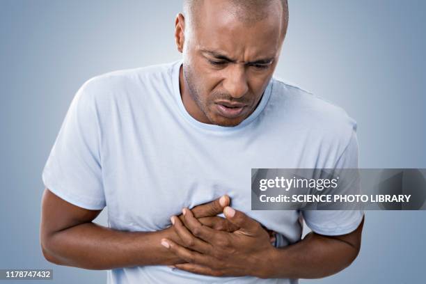 man clutching his chest in pain - sólo hombres maduros fotografías e imágenes de stock