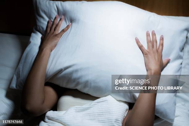 woman covering her face with pillow - insomnia stockfoto's en -beelden