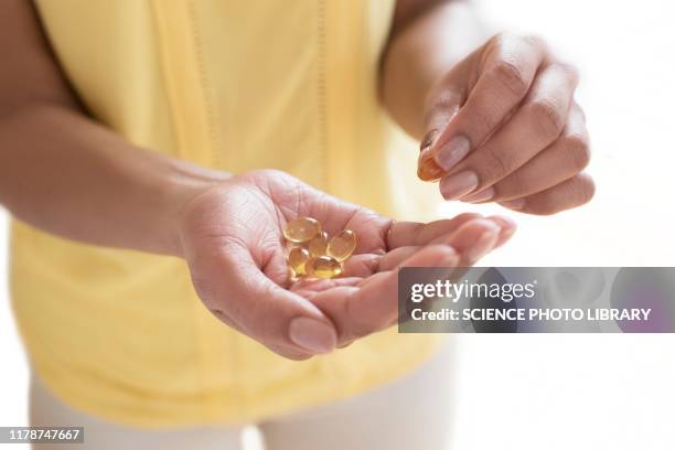 woman holding evening primrose capsules - hot flash stock pictures, royalty-free photos & images