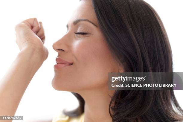 woman smelling perfume on her wrist - wrist stock pictures, royalty-free photos & images