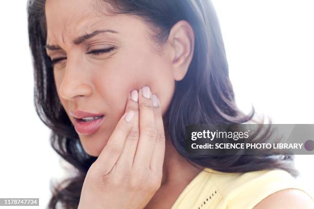 woman touching her cheek in pain - tandpijn stockfoto's en -beelden