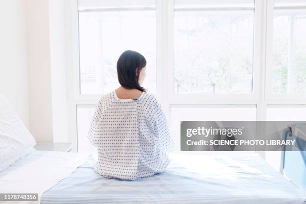 patient sitting on hospital bed, rear view - hospital bed stockfoto's en -beelden