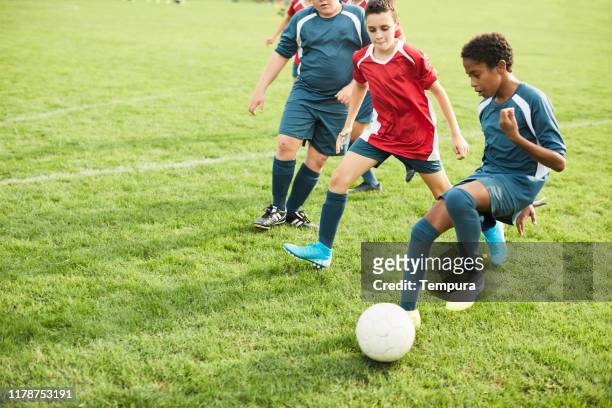 adolescente dribbla i suoi avversari durante una partita di calcio. - calcio di squadra foto e immagini stock
