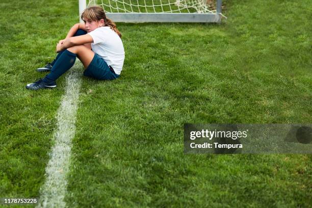 jong meisje zittend op het gras na een wedstrijd nederlaag. - side lines stockfoto's en -beelden