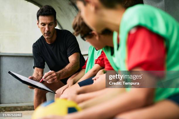 coach explaining the game plan - youth football team stock pictures, royalty-free photos & images