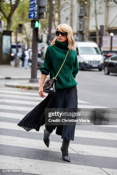 Gitta Banko is seen wearing a green oversized cashmere turtleneck sweater, a black pleated silk skirt- pants by Boscana, black boots by Yeezy, a...