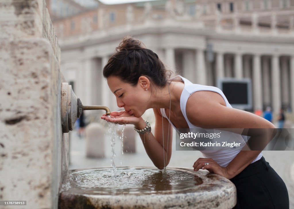 Woman drinking water from fountain at St. Peter's Square, Rome, Italy