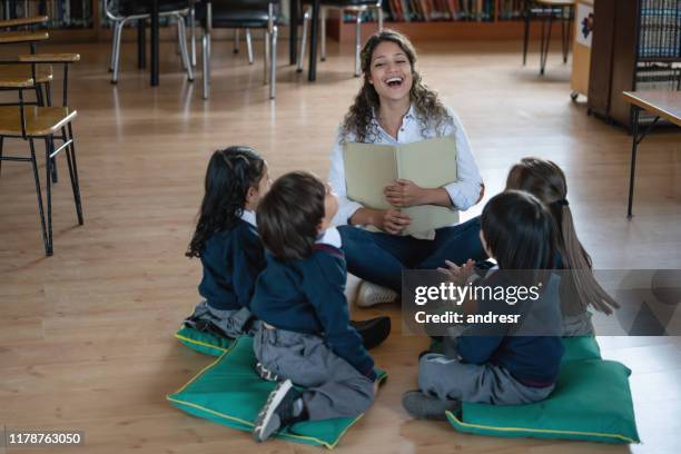 woman teaching a class to a group of elementary students - children circle floor stock pictures, royalty-free photos & images