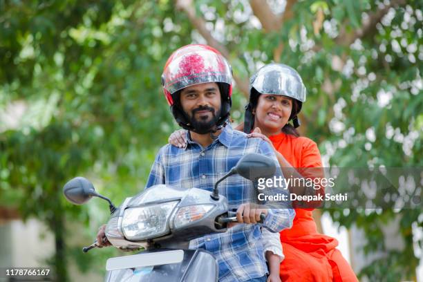 happy active mid adult couple on scooter stock photo - sports helmet stock pictures, royalty-free photos & images
