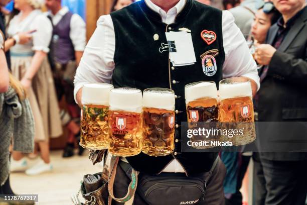 camarero llevando vasos de cerveza en el octoberfest en munich - oktoberfest fotografías e imágenes de stock