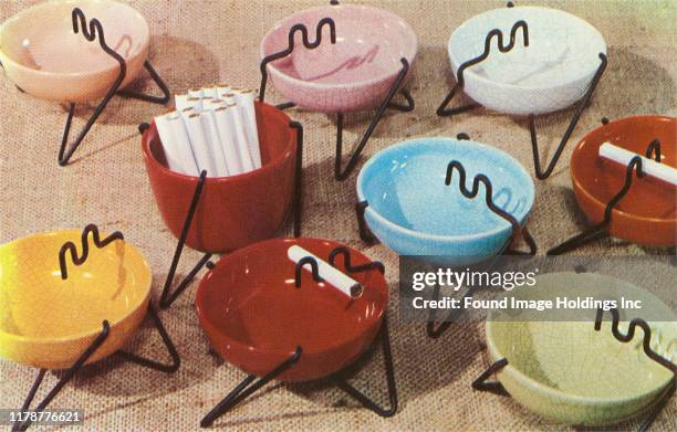 Selection of cloured ceramic ashtrays with black wire cigarette support.