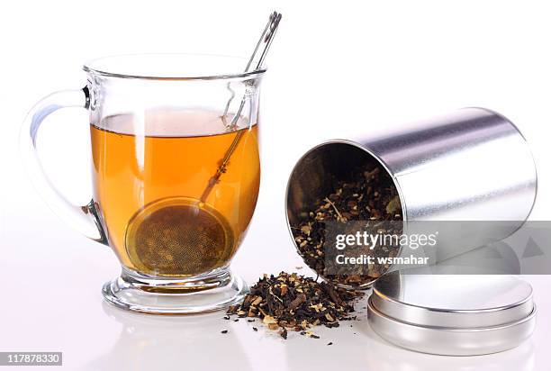 close-up of clear herbal tea with a can of grounded herbs - tea can stockfoto's en -beelden