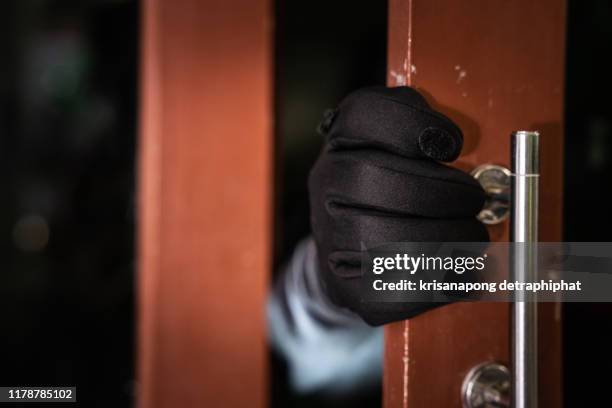 dangerous masked burglar with crowbar breaking into a victim's home door - voleur photos et images de collection