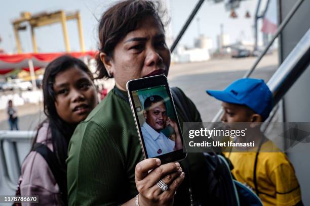 Dewi Manik, shows a photo of her husband, Rudy Lumbantoruan, who was a victim on board Lion Air flight JT-610 as she boards the Indonesian Navy ship...