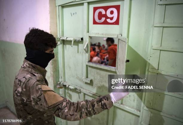 Member of the Syrian Democratic Forces stands guard in a prison where men suspected to be afiliated with the Islamic State group are jailed in...