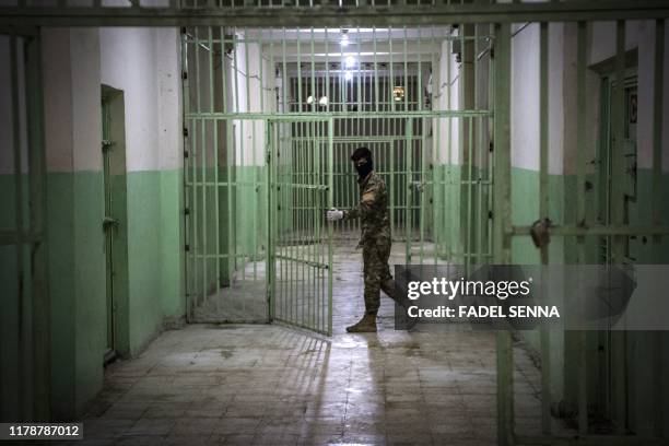 Member of the Syrian Democratic Forces stands guard in a prison where men suspected to be afiliated with the Islamic State group are jailed in...